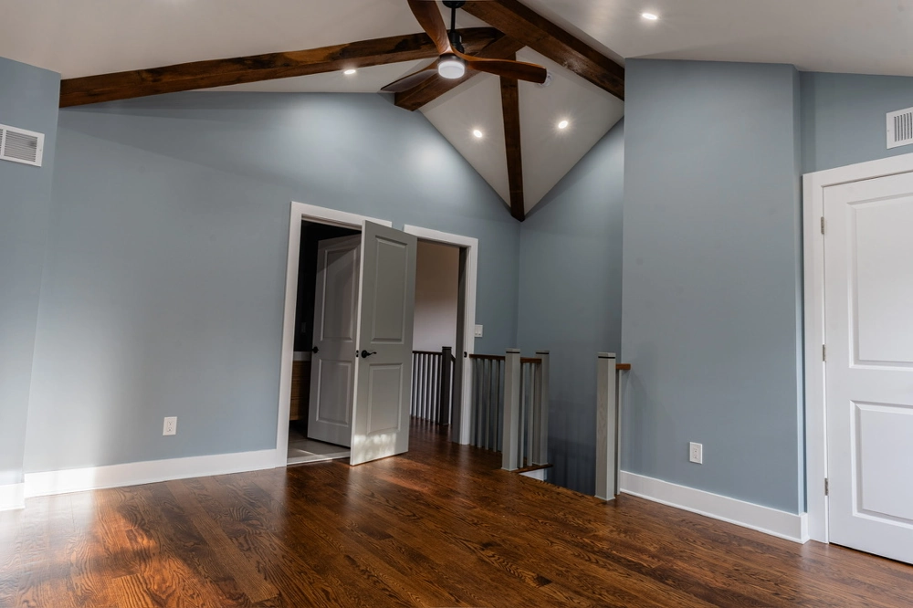 Hardwood Flooring in remodeled room with new oak floors, blue painted walls, vaulted ceiling beams and ceiling fan