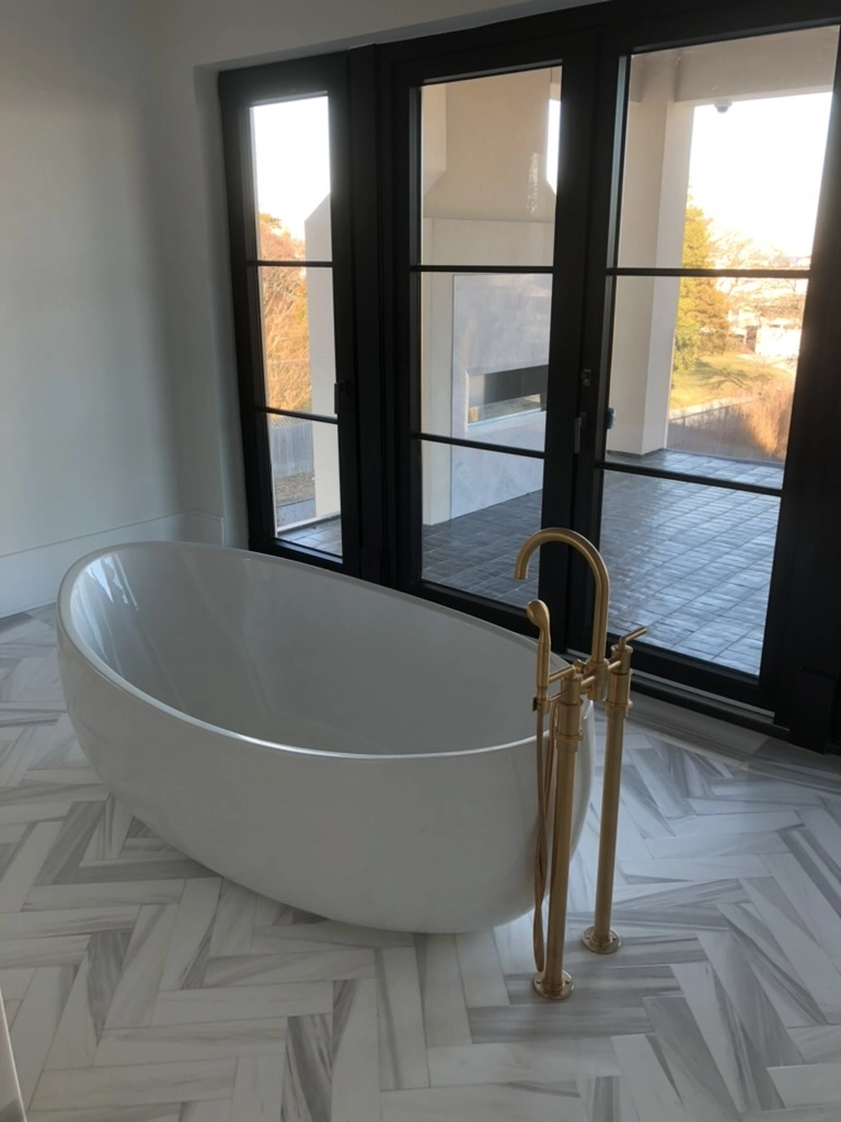 Freestanding bathtub with gold faucet on chevron tile floor and black-framed windows in modern bathroom – Bathroom Renovation