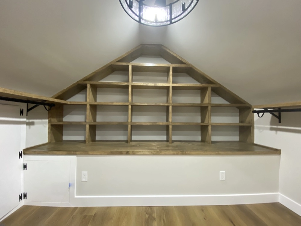 Custom built-in wooden shelving and bench under sloped ceiling showcasing Finish Carpentry