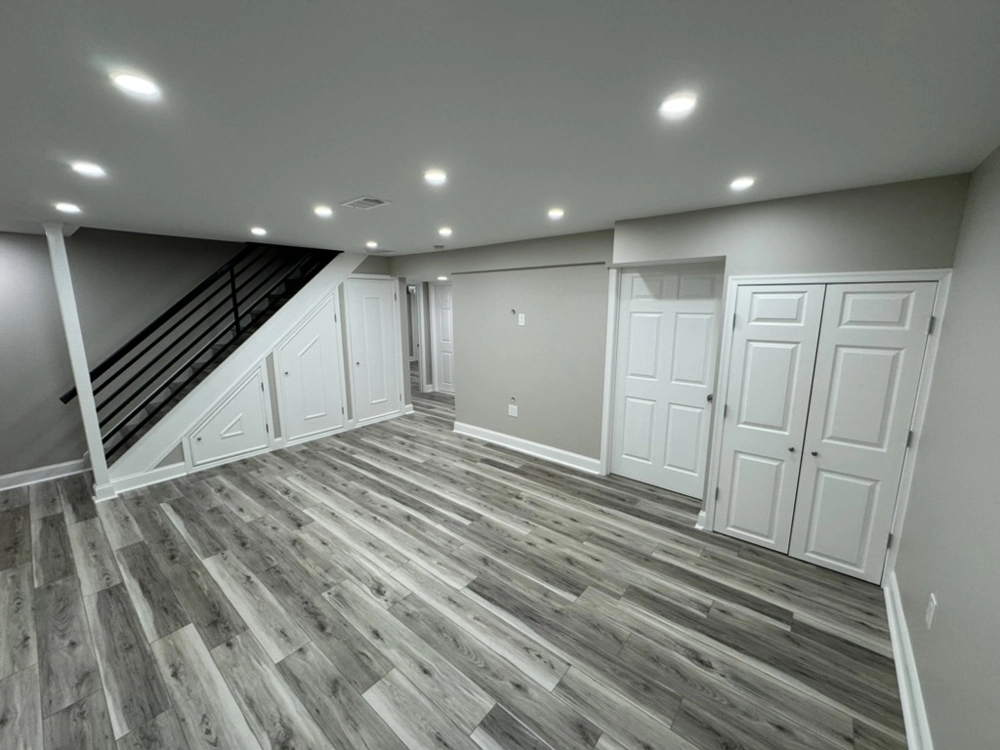 Finished basement with vinyl flooring, recessed ceiling lights and white doors highlighting Basement Finishing