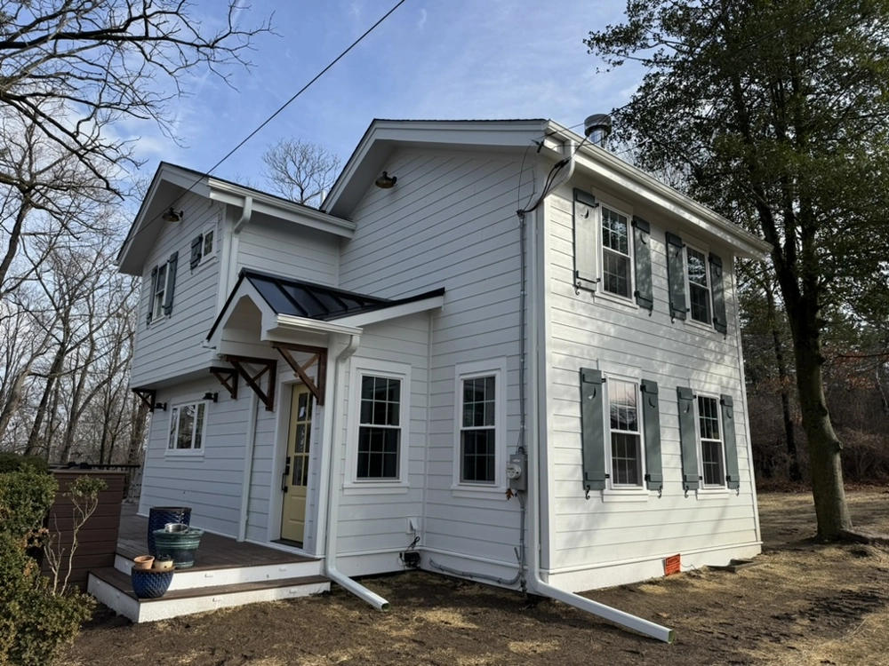 Two-story home with fresh white siding installation and shuttered windows