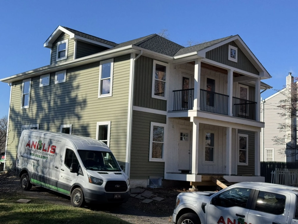 Two-story home with green fiber cement siding, white trim and company vans in driveway, Siding Installation