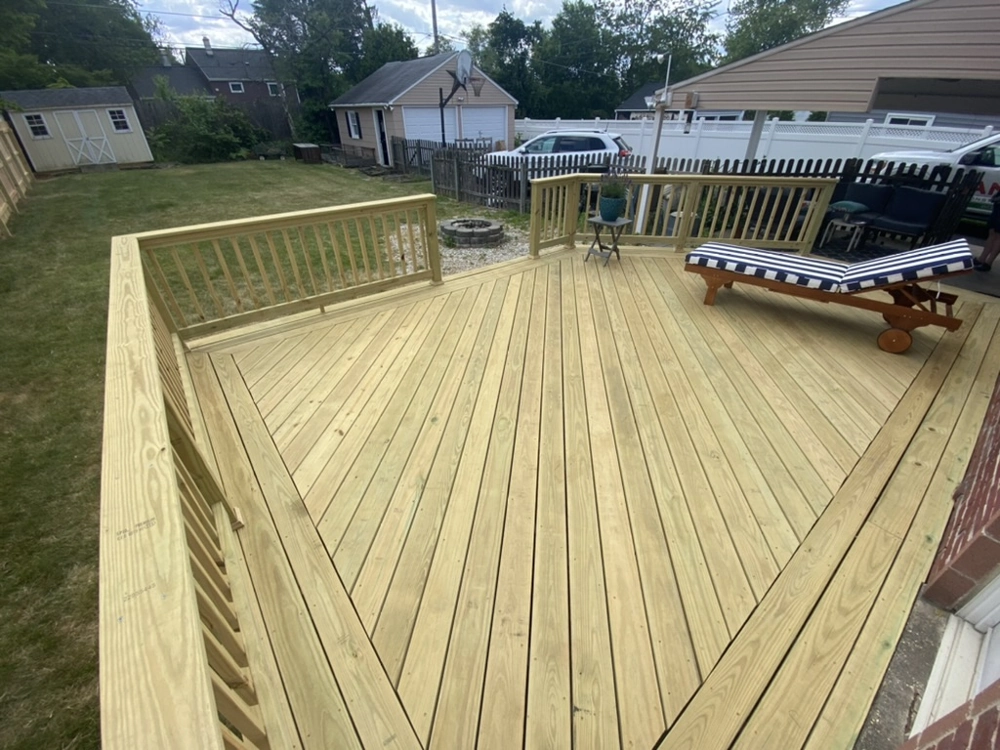 Wooden outdoor deck with railings, lounge chair and backyard view – Deck Installation