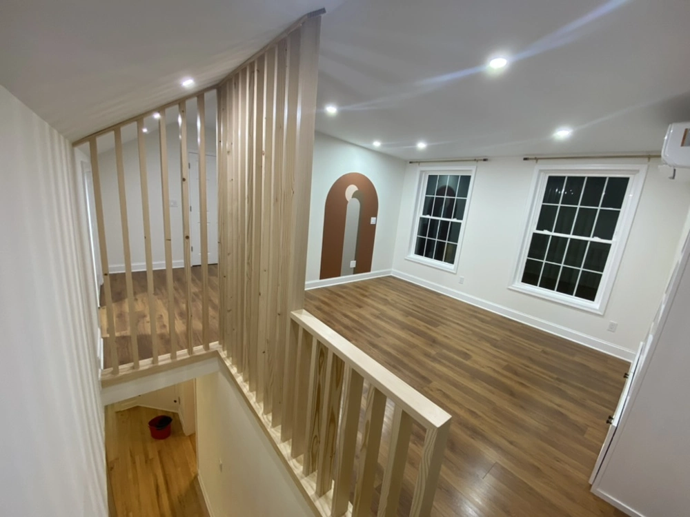 Open loft space with new wood-look flooring, white painted walls, wooden slat railing and arched accent wall – Flooring Installation