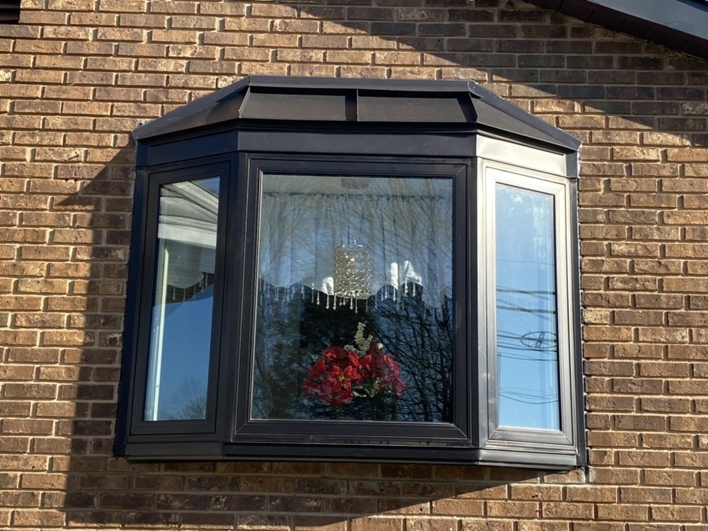 Black framed bay window installed in brick exterior wall, highlighting Window Installation service