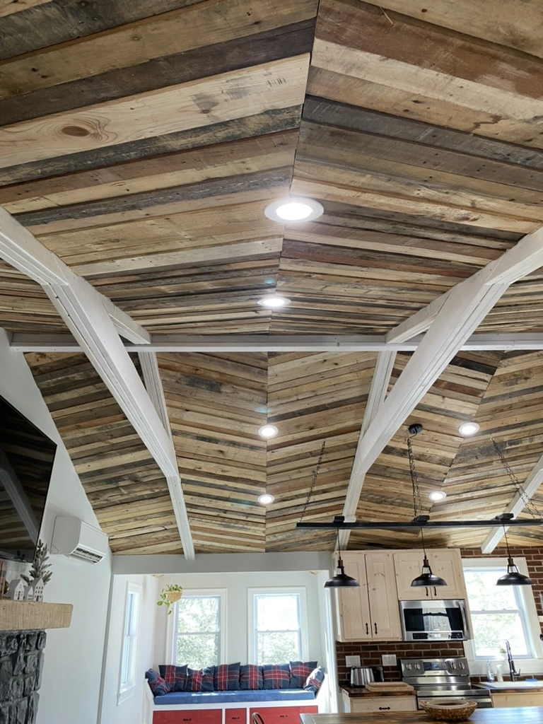 Reclaimed wood vaulted ceiling finish carpentry in remodeled kitchen with white beams and recessed lighting