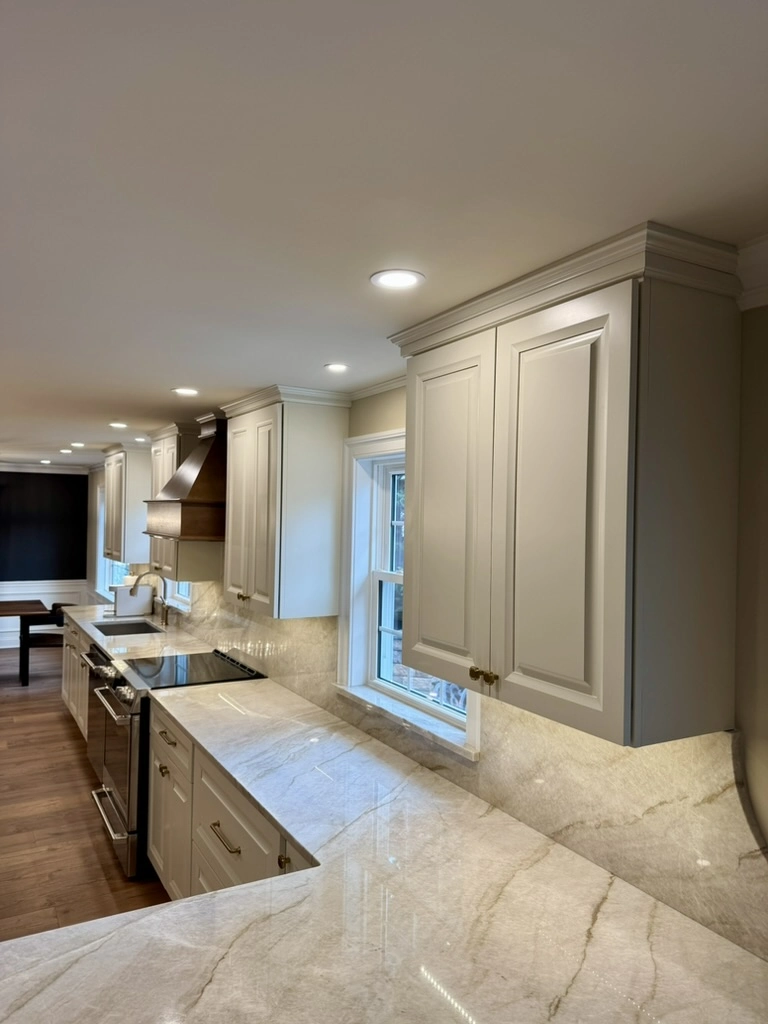 Modern kitchen interior with white cabinetry, marble countertops and backsplash, hardwood flooring – Kitchen Remodeling