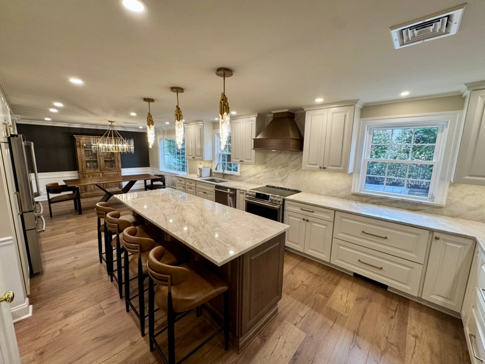 Modern kitchen showcasing Kitchen Remodeling: marble island with stools, hardwood flooring, white cabinets and pendant lights