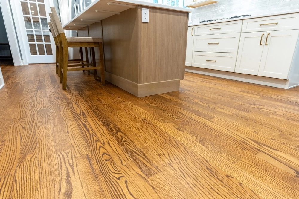 Hardwood Flooring installation in a modern kitchen with oak planks, island and white cabinets