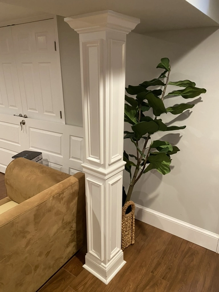 Finish Carpentry decorative basement column with crown molding and baseboards on hardwood flooring