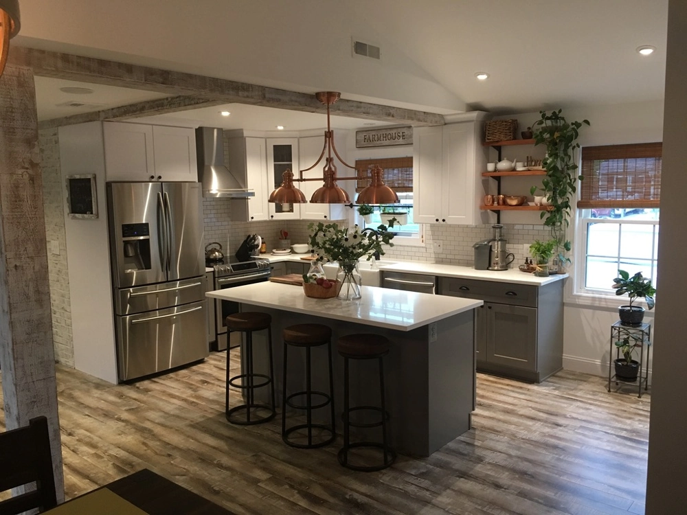 Spacious kitchen with island, stainless steel appliances, wood flooring, white cabinets and copper lighting – Kitchen Remodeling service