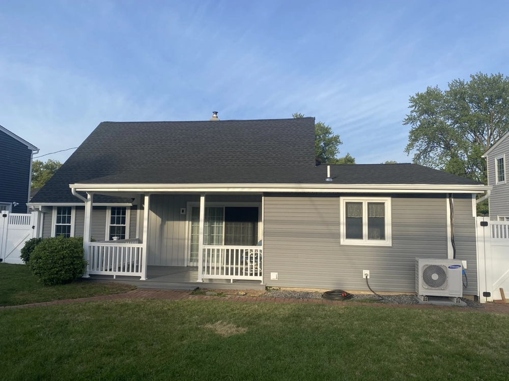 Rear view of house with new vinyl siding, porch railing, and shingle roof