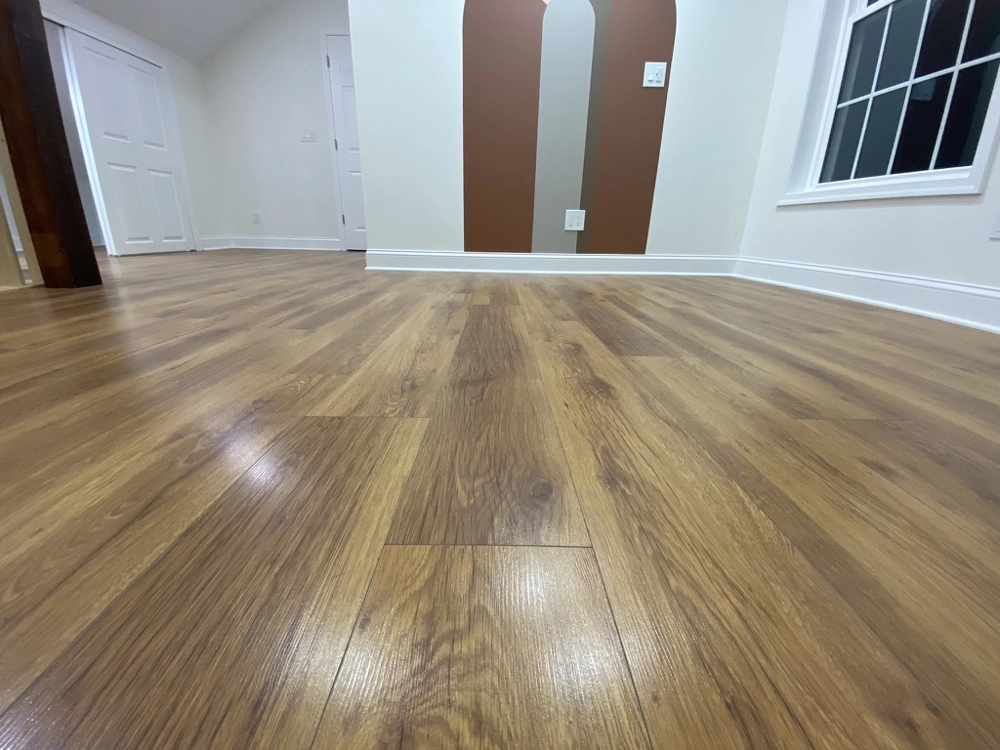 Vinyl Flooring installed as wood-look planks in an empty room with crisp white walls and baseboards