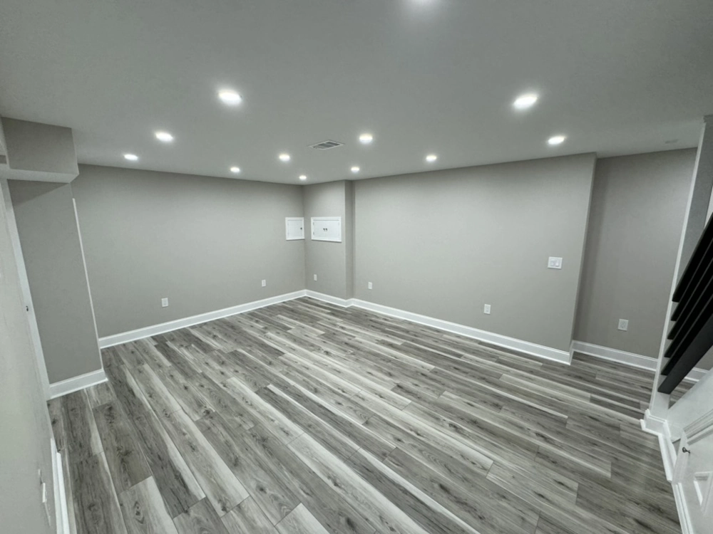 Finished basement interior with new vinyl flooring, painted drywall and recessed lights Basement Renovation