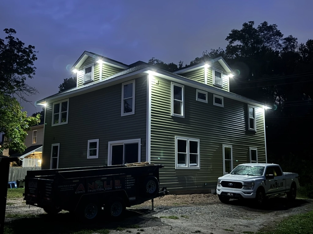 Two-story house at night after Vinyl Siding installation and Window Installation, illuminated by eaves lighting