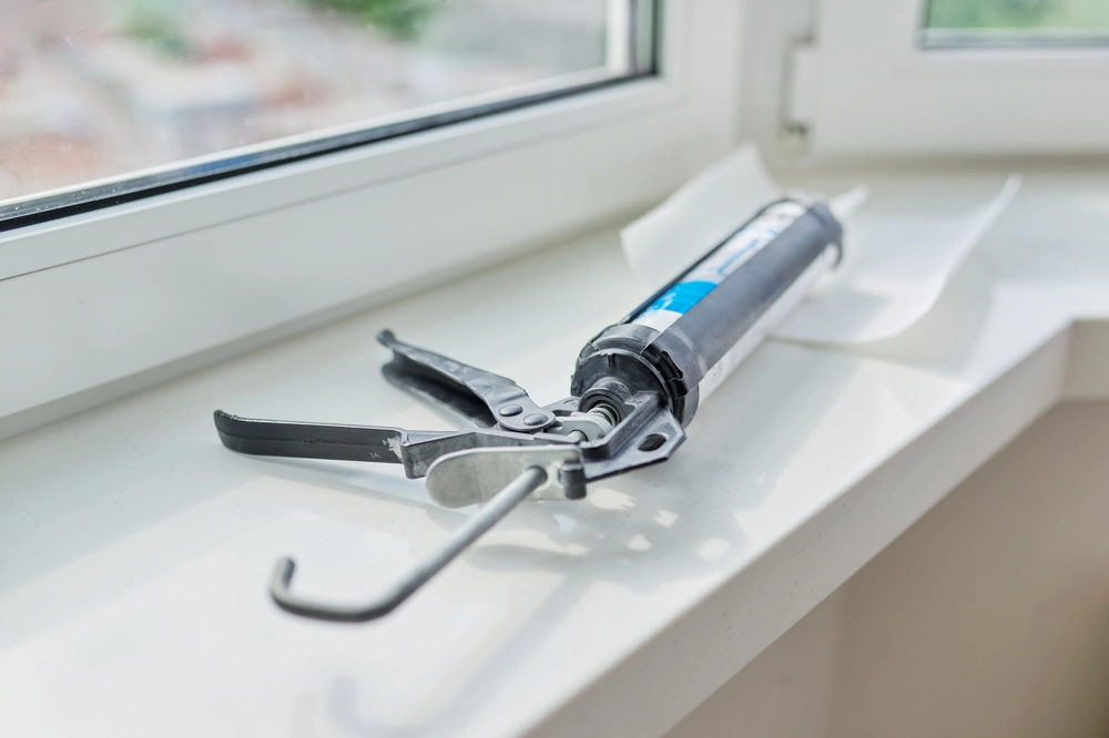 Caulking gun on a white windowsill during Window Installation