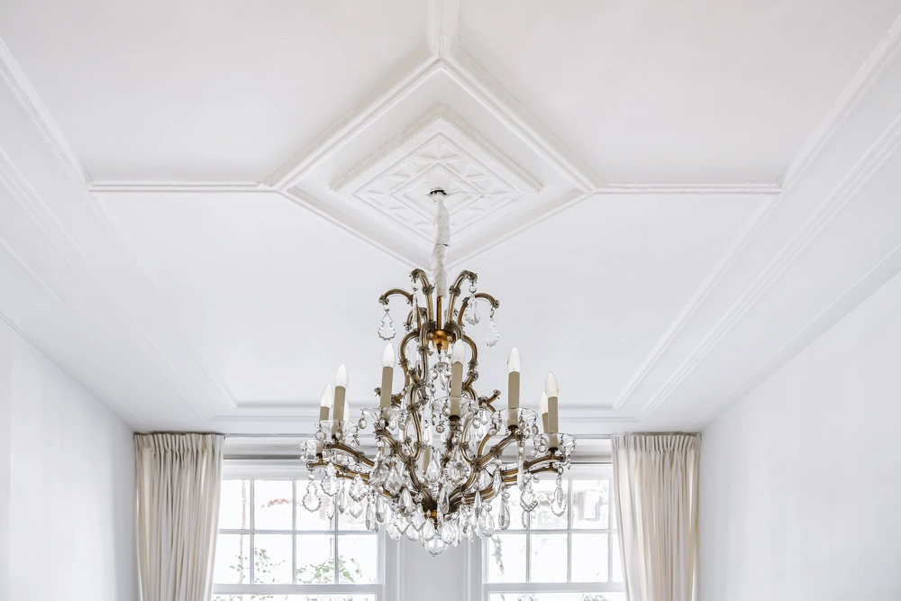 Ornate crystal chandelier hung from a white ceiling in a renovated space – Electrical Work