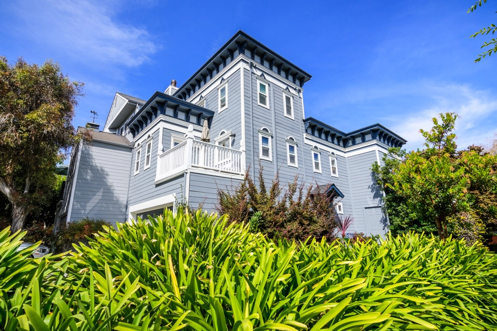 Gray two-story house with white trim, landscaped front yard, highlighting Exterior Painting service