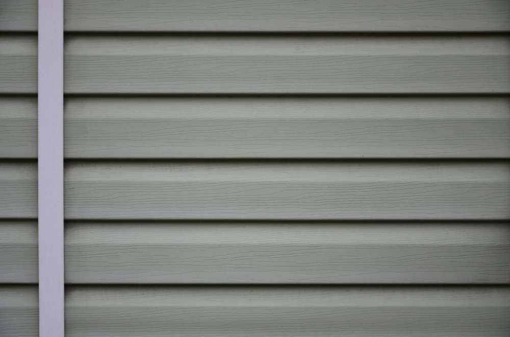 Close-up of grey horizontal vinyl siding panels with white trim, showcasing vinyl siding installation