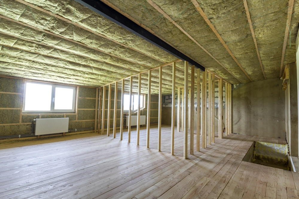 Insulated attic space with exposed studs and new hardwood floor under renovation
