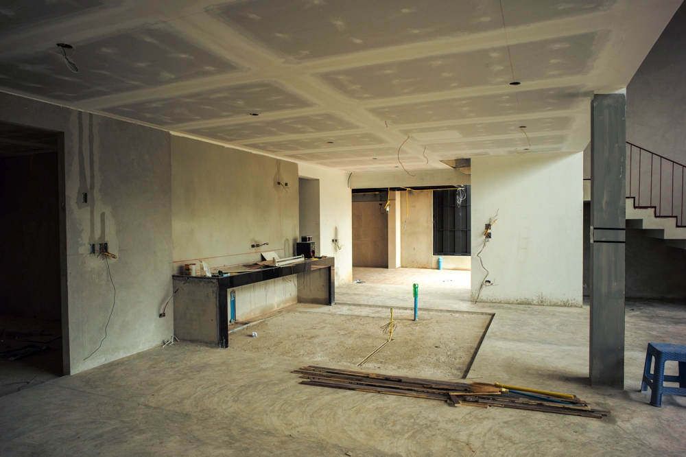 Open living space under Drywall Installation with exposed ceiling panels, unfinished walls and rough plumbing