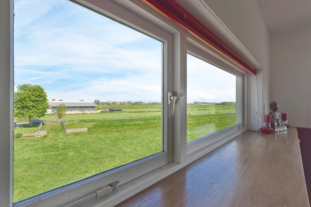 Interior view of tilt and turn window installation with wood sill, showing countryside landscape