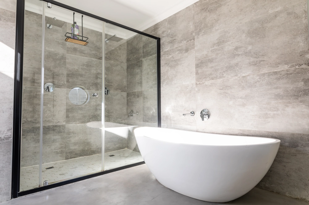 Bathroom Renovation showcasing a modern white freestanding bathtub and glass shower enclosure with grey tile walls