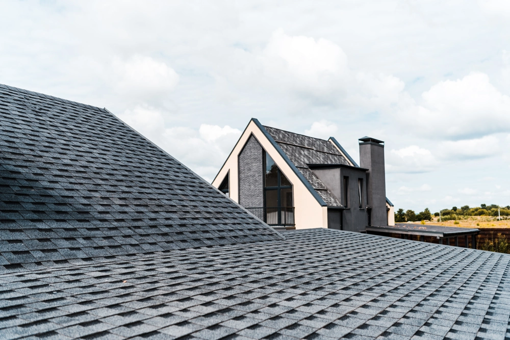 New dark asphalt shingle roofing on modern home gable and shed roof
