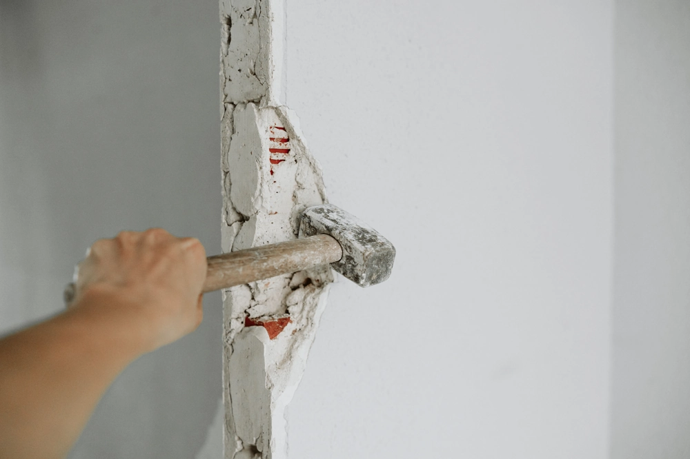 Person using sledgehammer to demolish an interior partition wall during Demolition