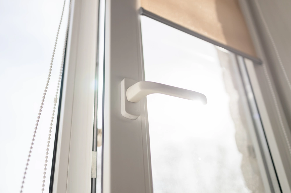 White tilt and turn window with handle and roller shade showcasing Tilt and Turn Windows installation