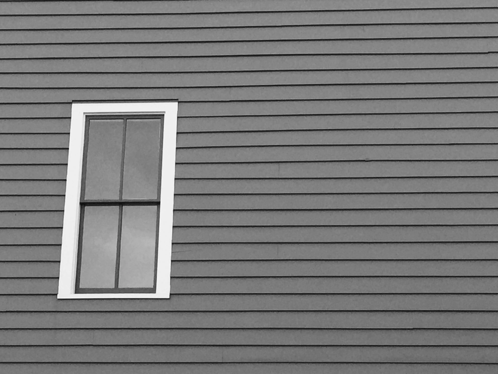 White-trim single-hung window installation on grey horizontal siding exterior wall